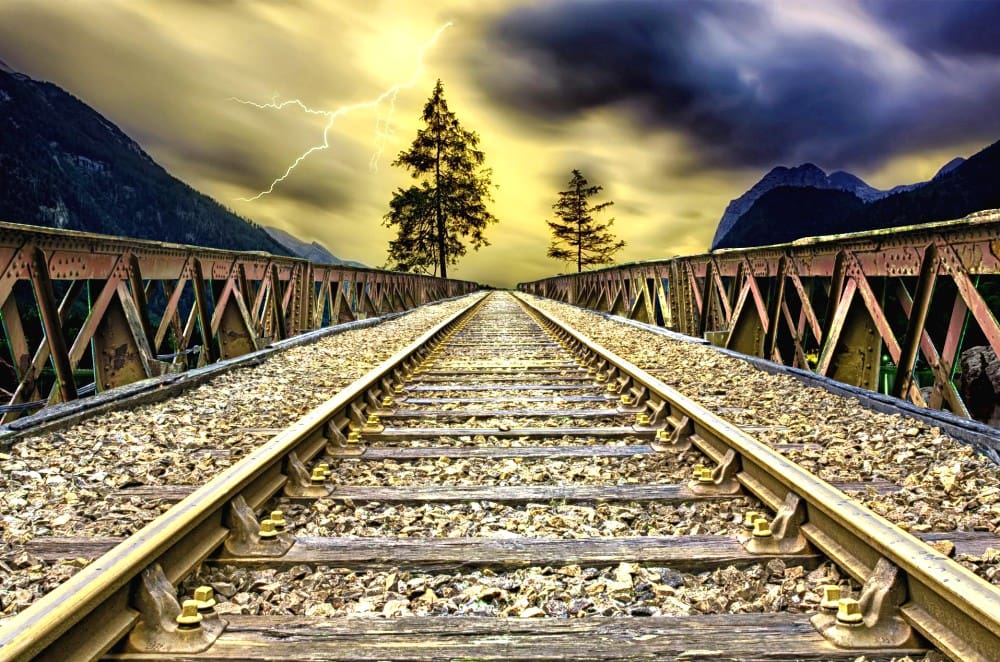 trilha de trem com tempestade ao fundo, representando a jornada humana